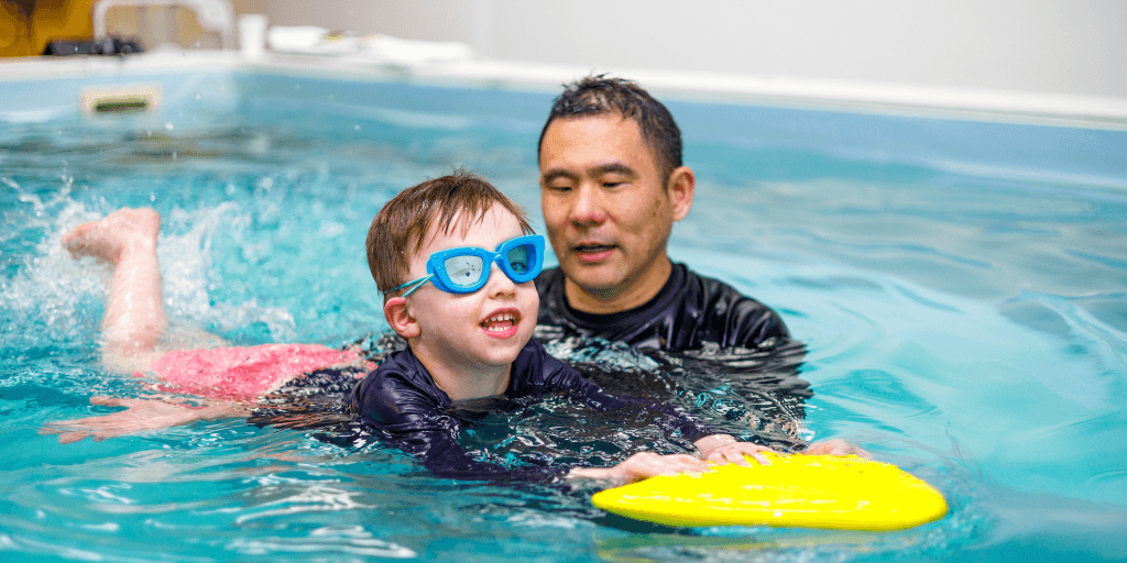 Special needs swimmer being assisted by swim instructor with swim skills during swim lessons at SafeSplash Swim School.