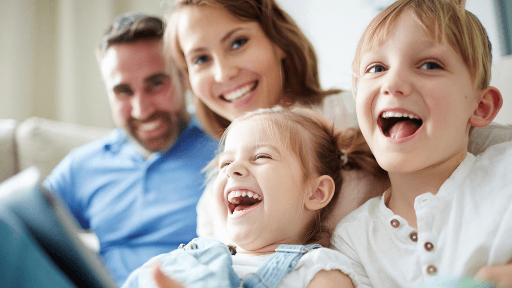 Family hanging out on the couch laughing