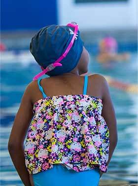 Young Girl Sitting on Pool Edge In Swimsuit and Swimcap