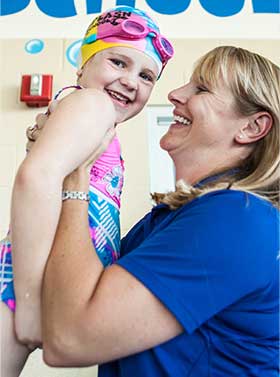 Safesplash Swim Instructor holding student up in the air
