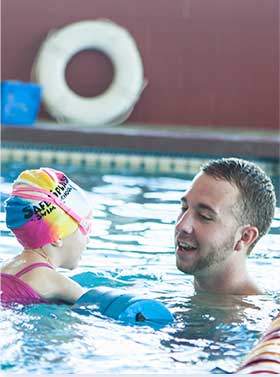 Swim Instructor using an floats with student during swimming lesson